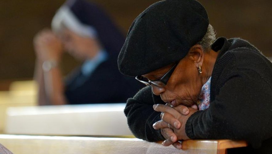 Une femme prie dans l'église Regina Mundi de Soweto, le 6 décembre 2013, après la mort de Nelson Mandela