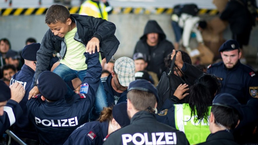 Des policiers autrichiens aident des migrants à franchir la frontière entre l'Autriche et le Hongrie le 20 septembre 2015 à Nickelsdorf