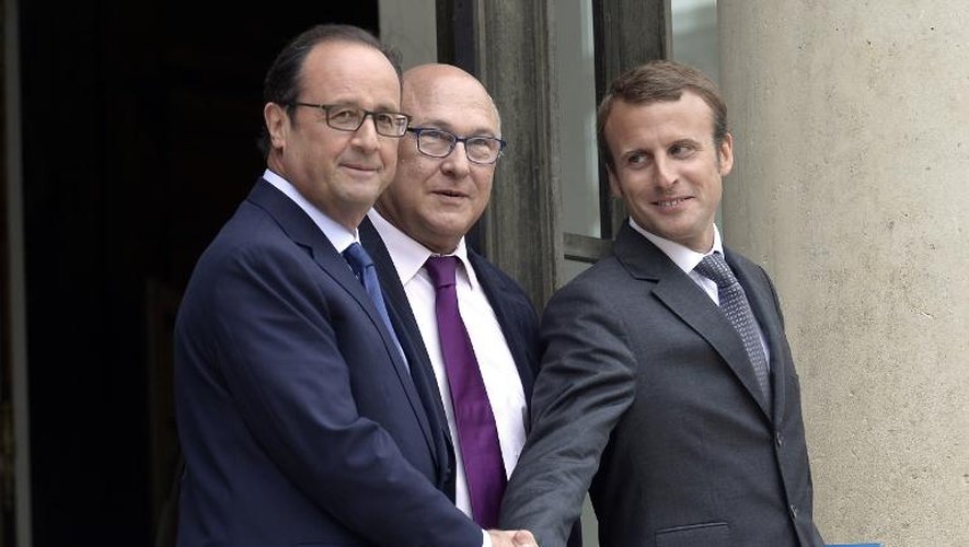 Le nouveau ministre de l'Economie Emmanuel Macron (d) serre la main de François Hollande sous les yeux du ministre des Finances Michel Sapin, le 27 août 2014 sur le perron de l'Elysée