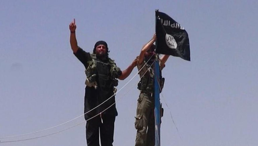 Photo d'archive extraite du compte twitter jihadiste Al-Baraka news le 11 juin 2014 montrant des militants de l'EI et leur drapeau noir sur un fort situé entre la province irakienne de Ninive et la ville syrienne de Al-Hasakah
