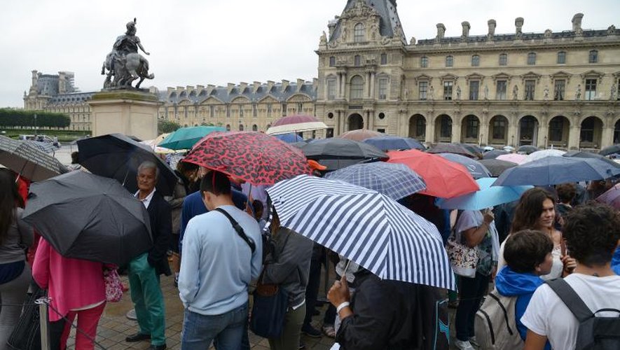 Des visiteurs font la queue sous la pluie devant le musée du Louvre à Paris le 8 août 2014