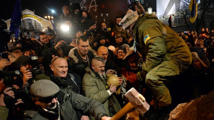 Un manifestant frappe la statue de Lénine qui vient d'être déboulonnée, dans le centre de Kiev, le 8 décembre 2013