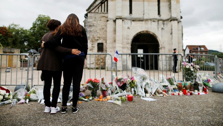 Des gens devant un mémorial improvisé devant l'église de Saint-Etienne du Rouvray, le 27 juillet 2016