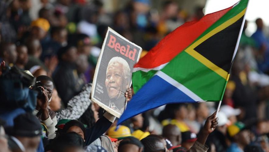 Un portrait de Mandela et un drapeau sud-africain brandi lors de la cérémonie d'adieu le 10 décembre 2013 au stade Soccer City de Soweto