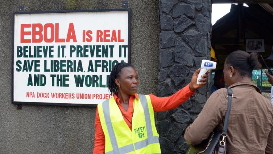 Un agent de sécurité contrôle la température d'une femme à l'entrée du port de Monrovia, au Liberia, le 29 août 2014