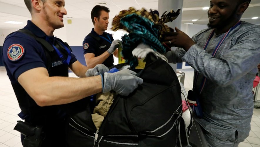 Un douanier aide un passager à refaire son sac après une fouille à l'aéroport Roissy-Charles-de-Gaulle, le 26 juillet 2016
