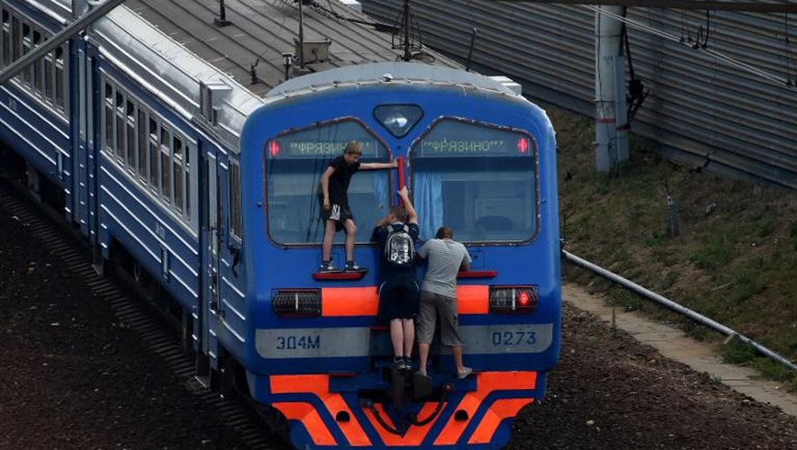 Des jeunes accrochés à un train près de la gare de Losinoostrovskaya, dans la banlieue de Moscou, le 25 juillet 2014