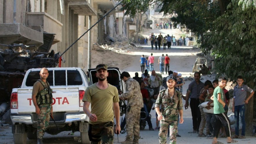 Les forces pro-régime sécurisent une route tandis que des civils entrent, le 29 juillet 2016, dans le quartier de Bani Zeid, dans le nord d'Alep, repris la veille aux rebelles