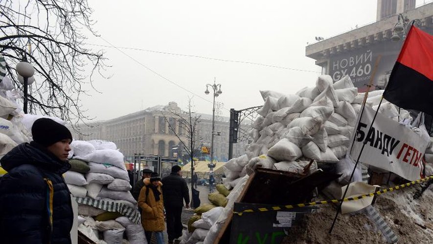 Des pietons passent entre les barricades érigées par les manifestants le 12 décembre 2013 à Kiev