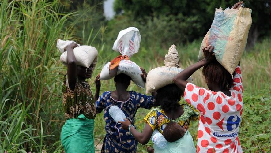 Des Centrafricaines portent des rations d'aide alimentaire près d'un camp de déplacés à Bangui le 13 décembre 2013