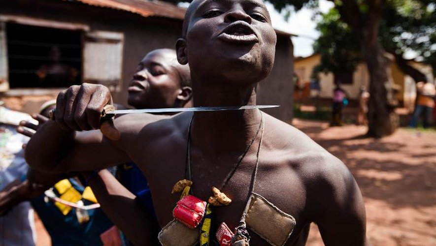 Un combattan anti-balaka mime avec un couteau le sort qu'il réserve aux rebelles Séléka, le 14 décembre 2013 à Bangui