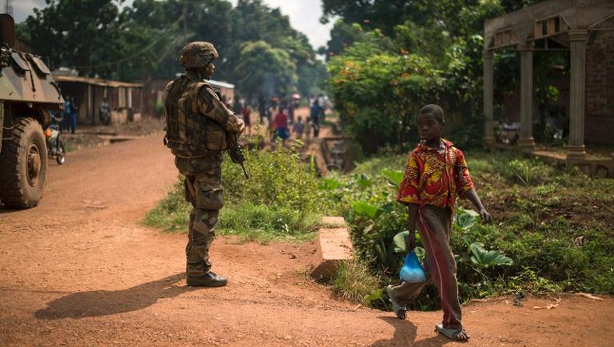 Un garçon passe à côté d'un soldat français en patrouille, le 14 décembre 2013 à Bangui