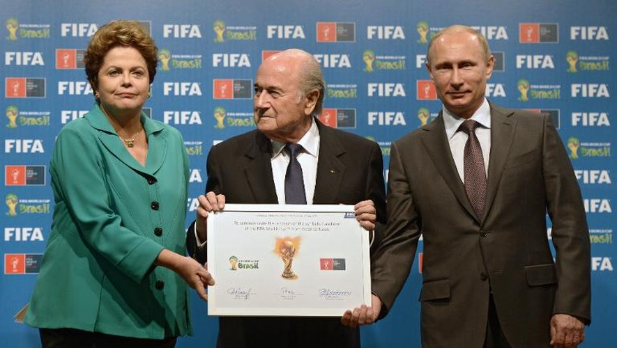La présidente du Brésil Dilma Rousseff (g) et son homologue russe Vladimir Poutine (d), aux côtés de Joseph Blatter, présentent le certificat de la Coupe du monde 2018, prévue en Russie, le 13 juillet 2014 à Rio de Janeiro