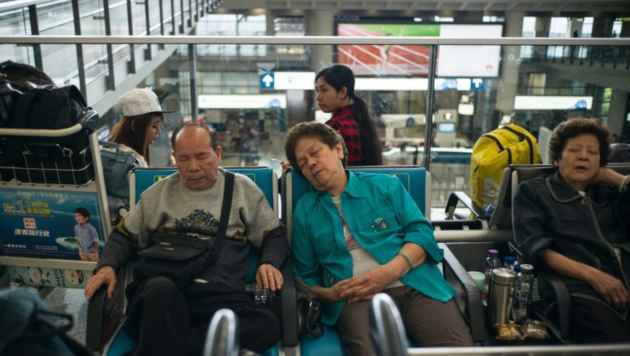 Des passagers se reposent en attendant des nouvelles de leur vol, à l'aéroport d'Hong Kong le 2 août 2016