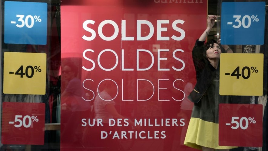 Une vendeuse s'occupe de la vitrine d'un magasin au lancement de la saison des soldes d'été le 22 juin 2016 à Strasbourg. Les pancartes affichent des réductions de 30, 40 et 50%