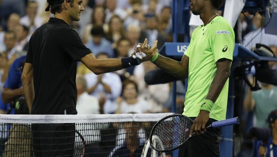 Gaël Monfils (d) et Roger Federer se serrent la main après le match de quarts de finale de l'US Open remporté par le Suisse, le 4 septembre 2014 à New York