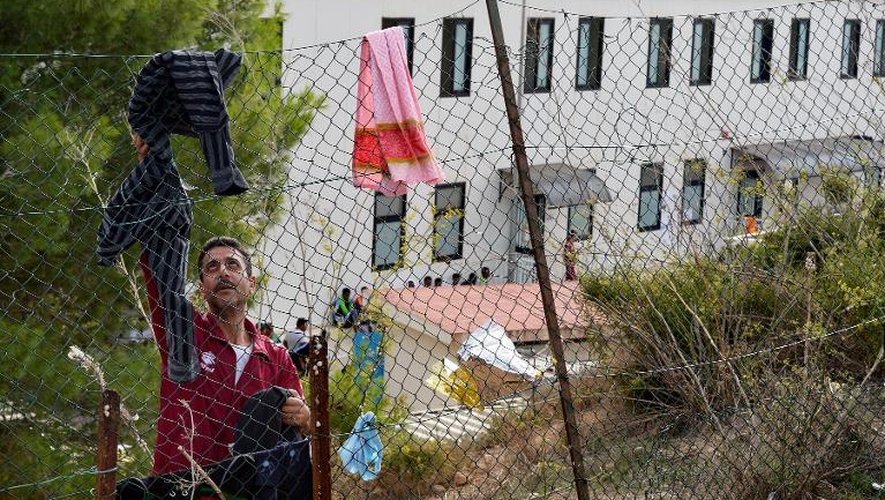 Un homme met à sécher du linge sur une grille dans un centre d'hébergement temporaire de Lampedusa (Italie) le 4 octobre 2013