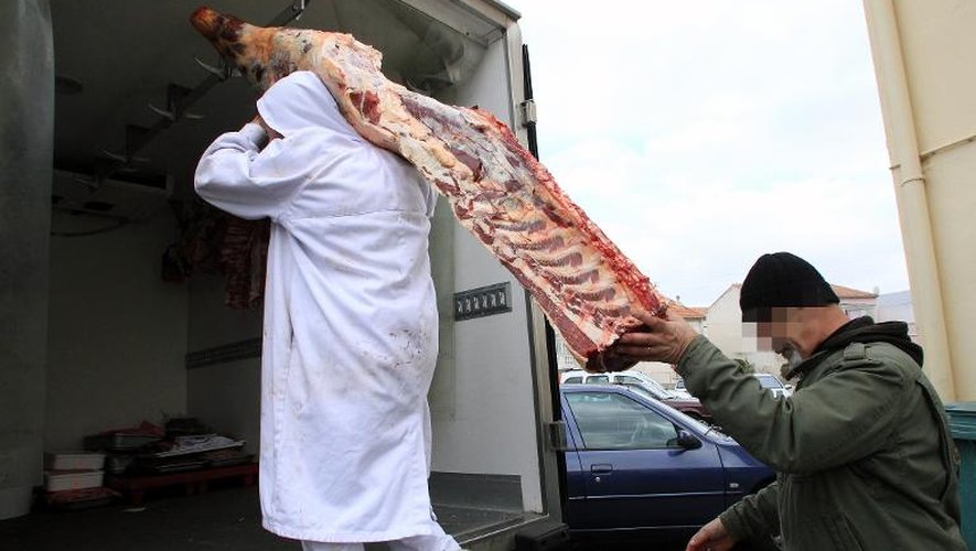 Un employé réquisitionné transporte un quartier de viande sous la surveillance d'un policier le 16 décembre 2013 à Narbonne