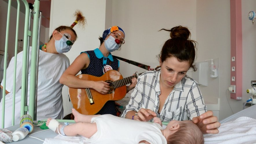Des clowns de l'association "Le Rire Medecin" avec un enfant malade le 25 juillet 2016 à l'hôpital Necker à Paris