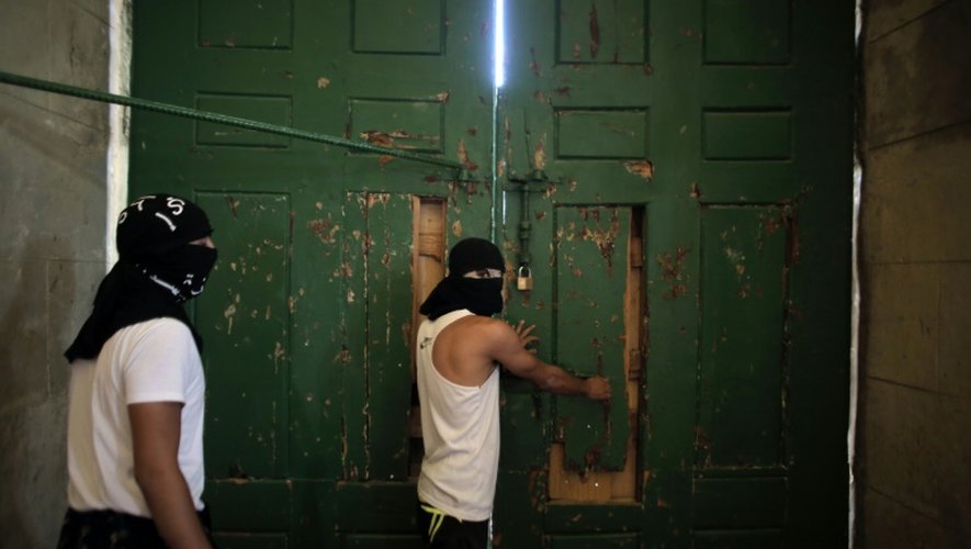 Des Palestiniens masqués tiennent fermées les portes de la mosquée le 27 septembre 2015 à Jérusalem