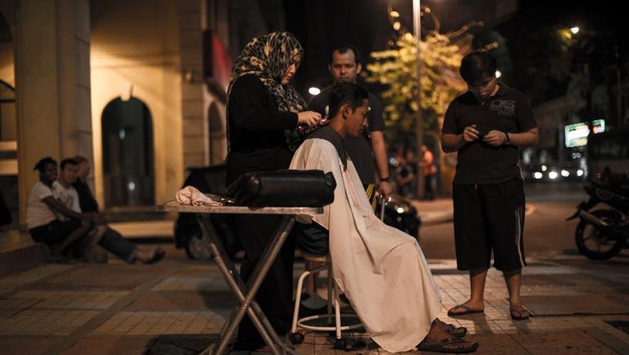 Azmina Burhan (g) coupe les cheveux à des sans-abris dans une rue de Kuala Lumpur