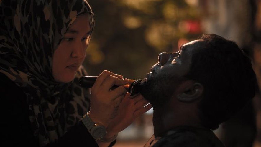 Azmina Burhan (g) coupe la barbe d'un sans-abris dans une rue de Kuala Lumpur