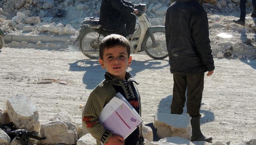 Un enfant syrien tient un livre devant son école après des raids du régime, le 22 décembre 2013 dans la ville de Marea, près d'Alep
