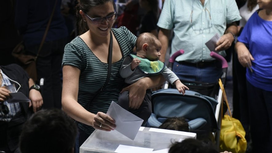 Une femme, son enfant dans les bras, vote pour les élections régionales espagnoles à Barcelone, le 27 septembre 2015