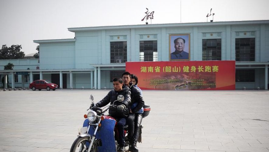 Des Chinois passent, le 25 décembre 2013, devant une gare sur laquelle s'affiche un portrait de Mao, dans la ville où il est né à Shaoshan dans la province de Hunan