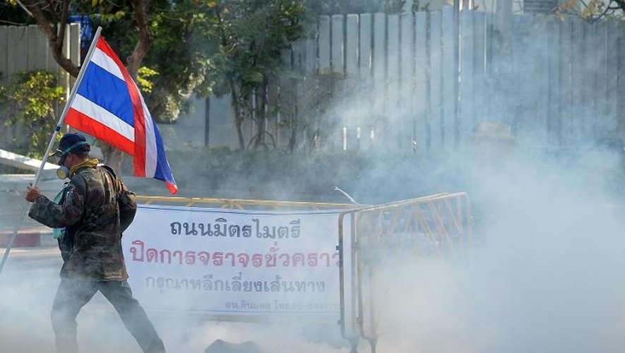 Un manifestant anti-gouvernemental tient un drapeau thaïlandais, le 26 décembre 2013 lors d'une manifestation aux abords du stade de Bangkok, où sont installés les bureaux d'enregistrement des candidatures pour les élections de février