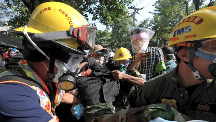 Des manifestants anti-gouvernementaux évacuent un blessé lors d'un rassemblement devant le stade de Bangkok, le 26 décembre 2013