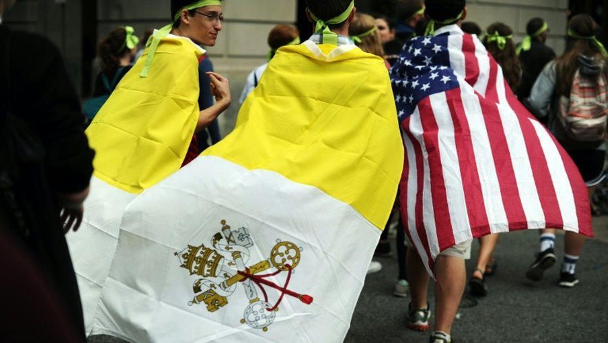 Des Américains avec le drapeau du Vatican et des Etats-Unis quittent l'endroit où le pape François a célébré une messe géante le 27 septembre 2015 à Philadelphie
