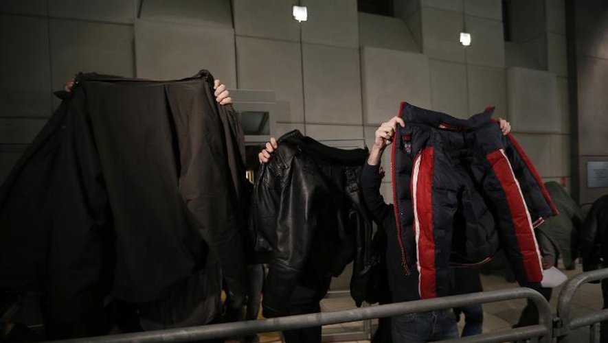 Des supporteurs de football masquent leur visage avec des vestes au moment de quitter le palais de justice de Nice, le 26 décembre 2013
