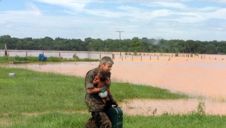 Un officier de l'armée brésilienne porte secours à un bébé dans une zone rurale affectée par de fortes pluies dans l'état de l'Espirito Santo, le 26 décembre 2013