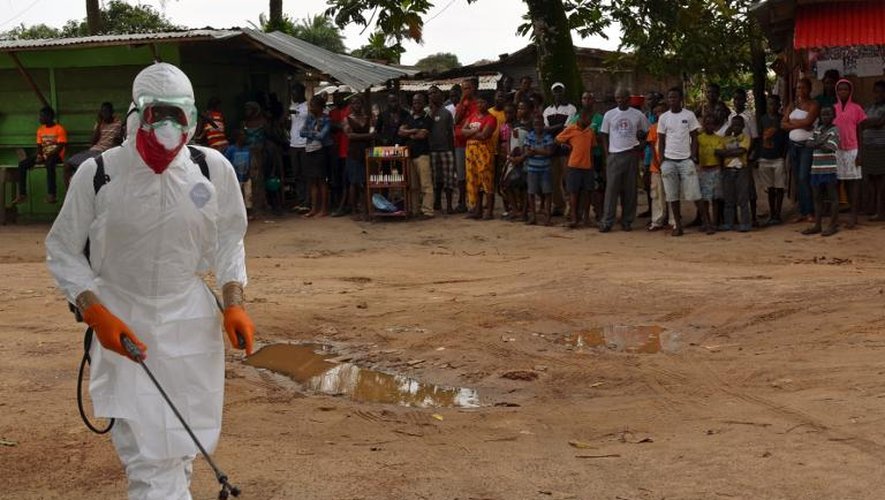Un agent santiaire, en combinaison de protection, procède à une opération de désinfection dans un quartier de Monrovia où une personne est décédée du virus Ebola, le 10 septembre 2014 au Liberia