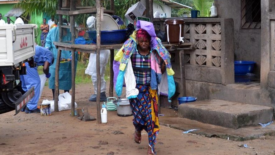 Une femme emporte les vêtements de son mari décédé du virus Ebola, le 10 septembre 2014 à Monrovia, au Liberia