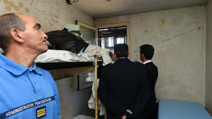 Le Premier ministre Manuel Valls (D), le ministre de la Justice Jean-Jacques Urvoas et le directeur de la maison d'arrêt de Nîmes Luc July (C) le 8 août 2016 dans une cellule de la maison d'arrêt de Nîmes