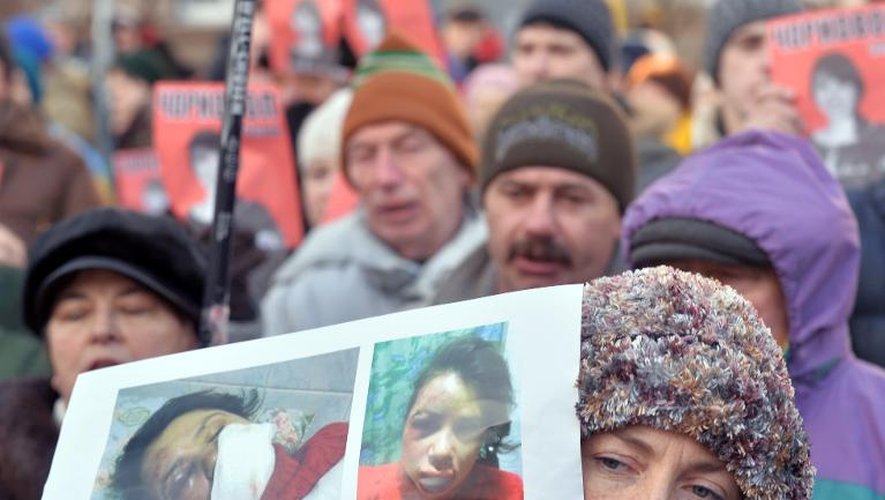 Une femme brandit des photos de la journaliste d'opposition agressée Tetiana Tchornovol, lors d'une manifestation contre le pouvoir, le 26 décembre 2013 à Kiev