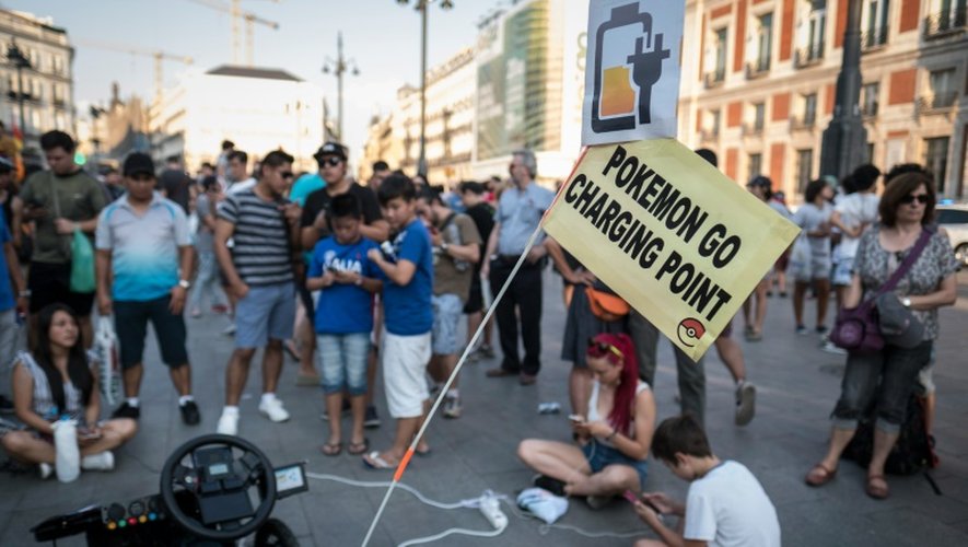 Des chasseurs de Pokémon rechargent leur téléphone portable sur une place de Madrid, le 28 juillet 2016