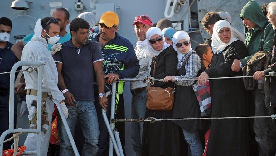 Des migrants débarquent d'un navire militaire italien après une opération de sauvetage, le 30 juin 2014 dans le port de Pozzallo, dans le sud de la Sicile