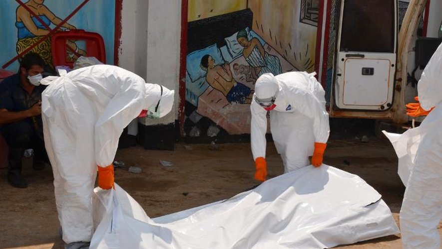 Des membres de la Croix-Rouge libérienne, vêtus de combinaison de protection, évacuent le corps d'une victime du virus Ebola, le 12 septembre 2014 à Monrovia