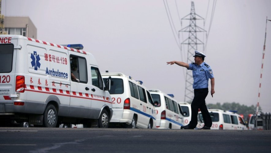 Un policier chinois indique le chemin à des ambulances à Dehui, le 3 juin 2013