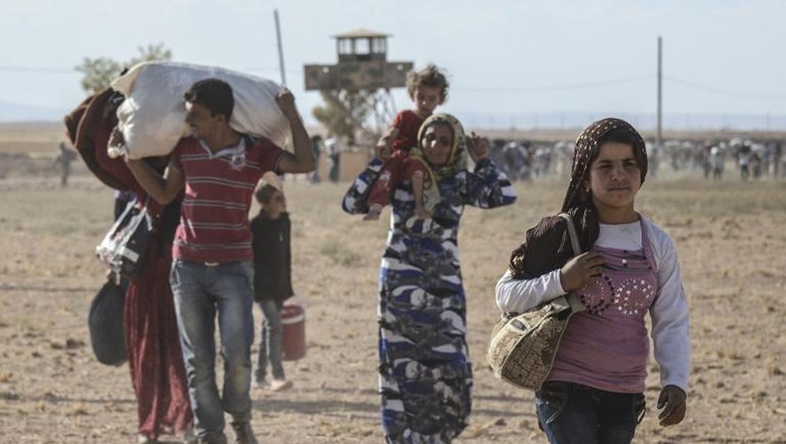 Des civils kurdes syrien franchissent la frontière avec la Turquie le 19 septembre 2014 près de Suruc dans la province Sanliurfa