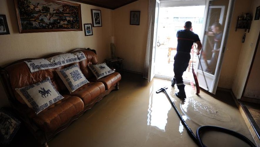 Un pompier aide des habitants à nettoyer leur maison envahie par les eaux à Alès, le 20 septembre 2014