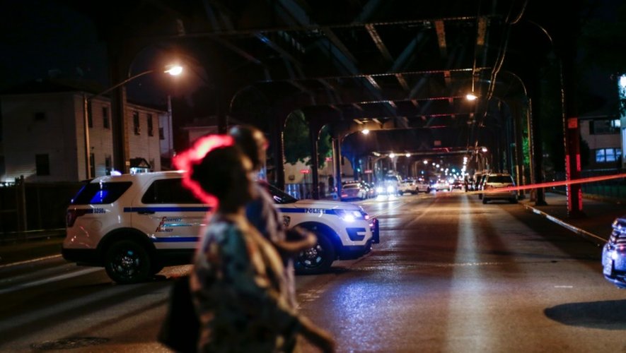 Des personnes passent devant une voiture de police à New York, le 13 août 2016