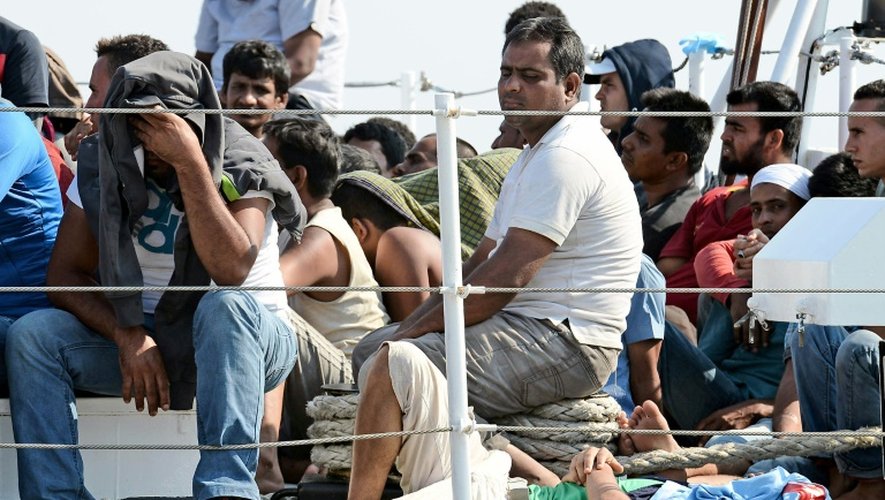 Des migrants attendent d'être débarqués d'un bateau des guardes-côtes italiens à leur arrivée le 7 août 2015 à Pozzalo en Italie
