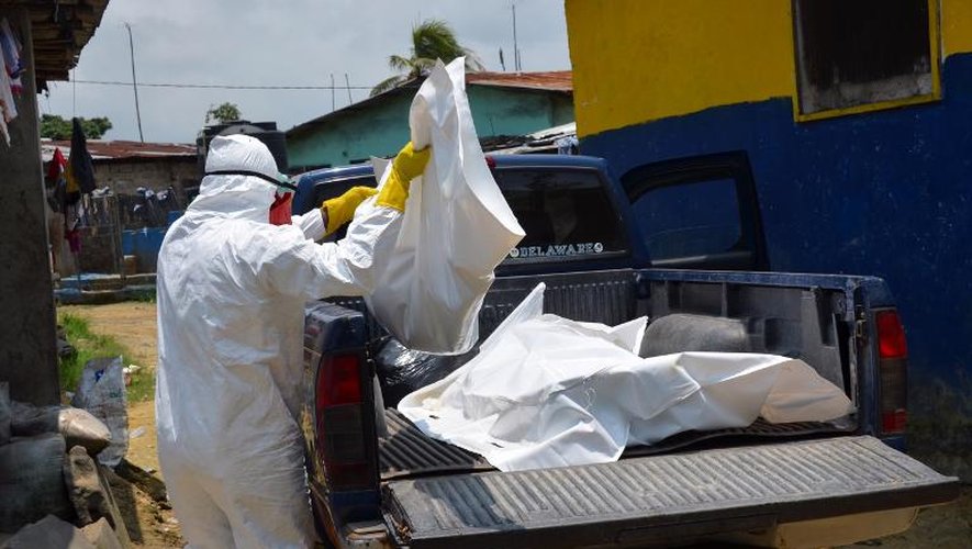 Un membre de la Croix-Rouge libérienne, en combinaison de protection, transporte le corps d'une victime du virus Ebola, le 12 septembre 2014 à Monrovia