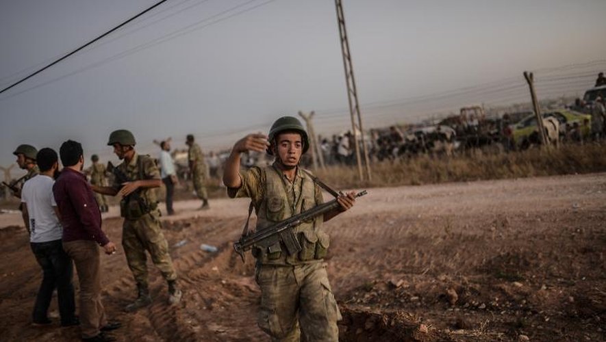 Des soldats turcs demandent aux réfugiés kurdes syriens de rester derriere la frontière le 21 septembre 2014 à Suruc dans la province Sanliurfa