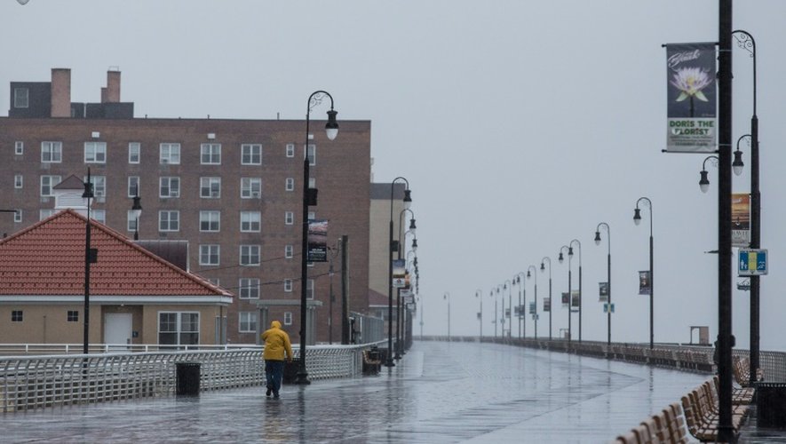 Un homme marche sous la pluie sur une esplanade de bord de mer alors que l'ouragan Joaquin s'approche de la côte est des Etats-Unis, le 2 octobre 2015 à Long Beach, près de New York