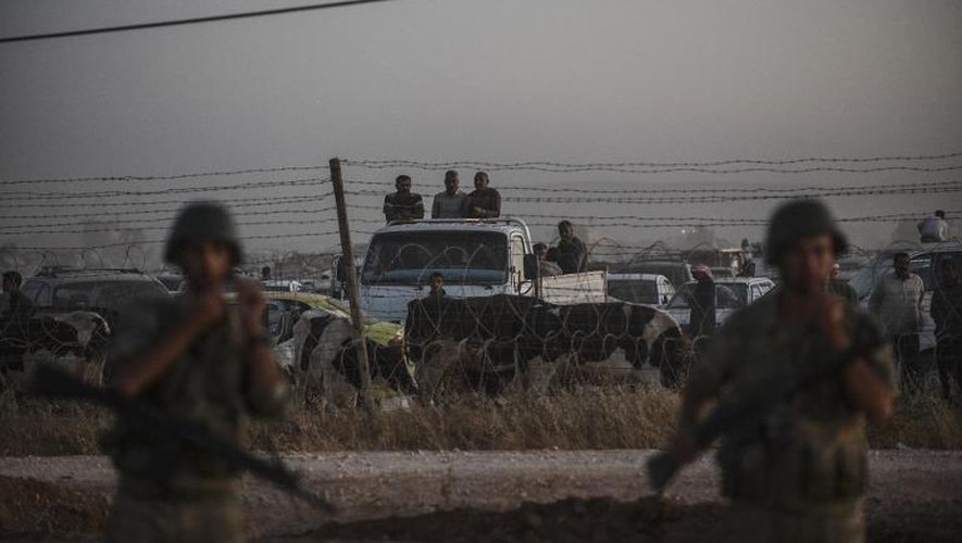 Des soldats turcs devant la frontière avec la Syrie, où attendent de passer des Kurdes de Syrie, chassés par l'avancée des jihadistes du groupe Etat islamique, le 21 septembre 2014 à Suruc, dans la province de Sanliurfa, dans le sud-est de la Turquie